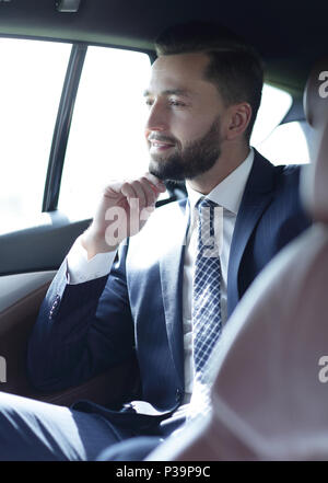 Smiling business man sitting in the back seat of a car Stock Photo