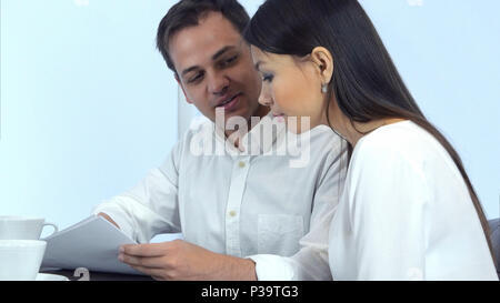 Two office colleagues discussing work and smiling while sitting in cafe Stock Photo