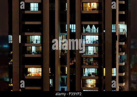 Night scene in big city - front view of high-rise building with windows of apartments in which light is burning. Stock Photo