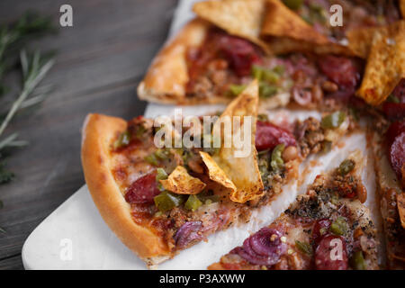 Fresh italian pizza. Food photography for design. Mexican pizza with chips, onion, hot jalapeno pepper on thin classic dough. Closeup photo of slice.  Stock Photo