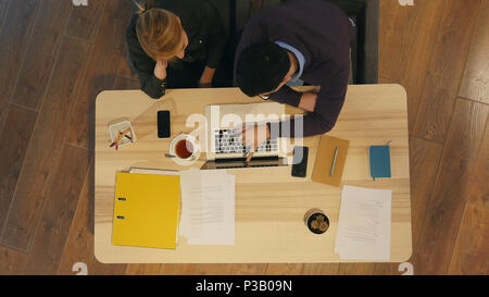 Manager and his pretty young colleague sitting in office and working on business presentation Stock Photo