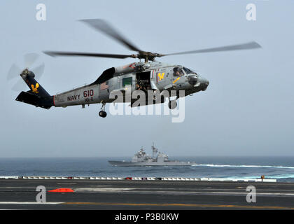 NORTH ARABIAN SEA (July 23, 2008) An HH-60H Seahawk assigned to the 'Golden Falcons' of Helicopter Anti-submarine Squadron (HS) 2 lands aboard the Nimitz-class aircraft carrier USS Abraham Lincoln (CVN 72) as the Ticonderoga-class guided-missile cruiser USS Mobile Bay (CG 53) maneuvers off Lincoln's starboard side. Lincoln is deployed to the U.S. 5th Fleet area of responsibility supporting Operations Iraqi Freedom and Enduring Freedom as well as maritime security operations. Stock Photo