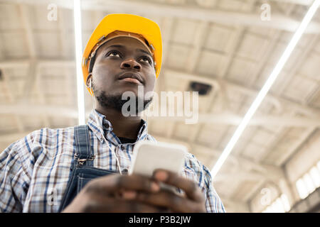 Pensive engineer texting sms at construction site Stock Photo
