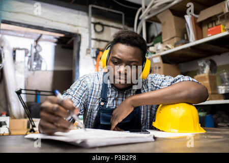 Thoughtful young engineer working in dark room Stock Photo
