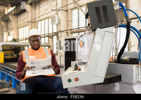 Relaxed machine operator reading newspaper Stock Photo