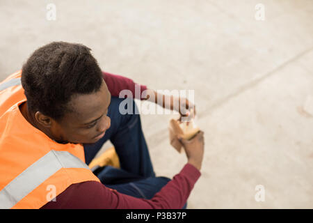 Calm worker in orange vest having lunch break Stock Photo