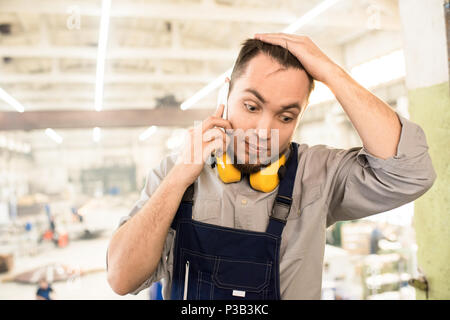 Puzzled builder calling on phone from construction site Stock Photo