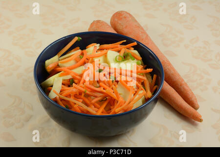 Shredded carrot and apple salad in blue bowl on table with tablecloth Stock Photo