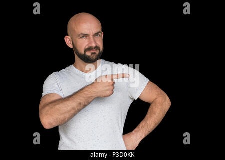 white bald man with a beard in a white T-shirt points finger to the side. isolated Stock Photo