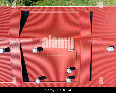 aerial view of red corrugated metal factory roof with tubes of ventilation systems Stock Photo