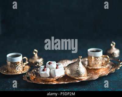 Turkish coffee with delight and traditional copper serving set on dark background. Assorted traditional turkish dilight or lokum and turkish coffee in metal traditional cups.Copy space.Selective focus Stock Photo
