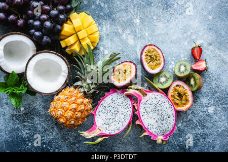 Group of exotic tropical fruits. Mango, dragon fruit, passion fruit, coconut, kiwi, pineapple and strawberry on concrete blue background. Fresh fruit 