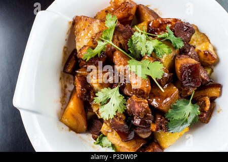 Chinese beef stew with young potatoes in sweet sauce, in white plate on black background Stock Photo