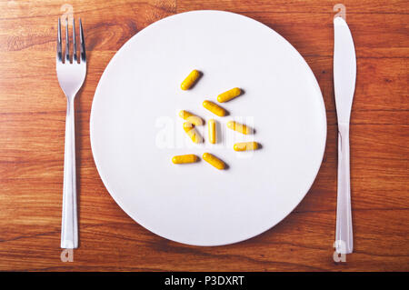 photograph of a plate with fork and knife with real medicine capsules on the plate and photographed again Stock Photo