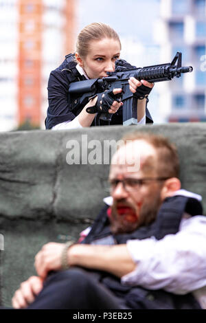 man and woman dressed as special agnets or killers with rifles on the roof Stock Photo