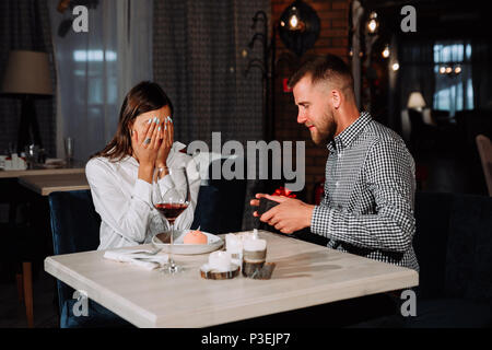 Portrait of happy and surprised young woman receiving present from boyfriend while sitting in cafe Stock Photo
