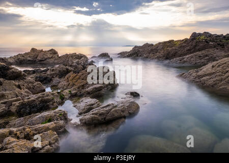 Sun breaking through clouds over the sea on the west coast of Anglesey, near Rhosneigr, Wales,UK Stock Photo