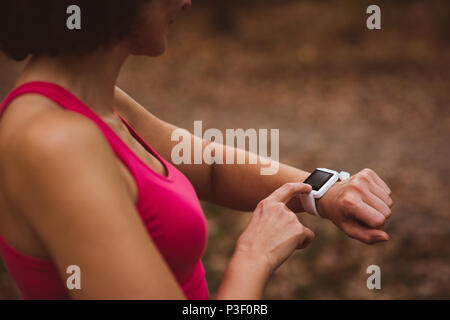 Woman using smart watch in forest Stock Photo