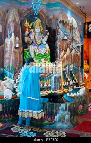 A Hindu worshiper makes an offering to  the god Shiva at the Tulsi Mandir temple in South Richmond Hill, Queens, New York. Stock Photo