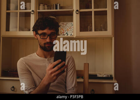 Man using mobile phone in kitchen Stock Photo