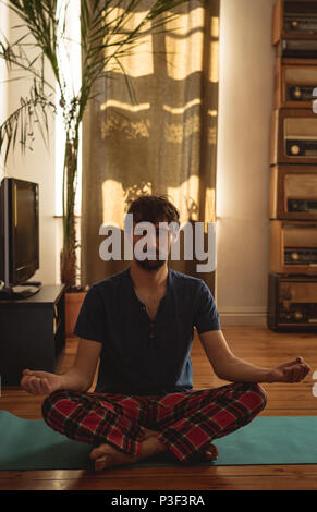 Man practicing yoga in living room Stock Photo