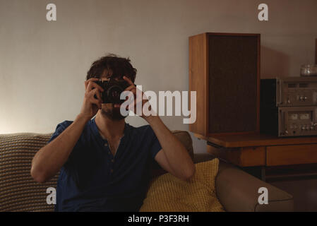Man taking photograph with vintage camera in living room Stock Photo