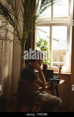 Man sitting with vintage camera at table Stock Photo