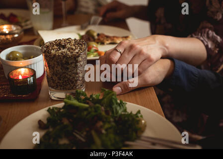 Couple holding hands while having meal Stock Photo