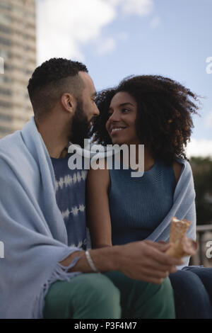 Couple wrapped in shawl looking at each other Stock Photo