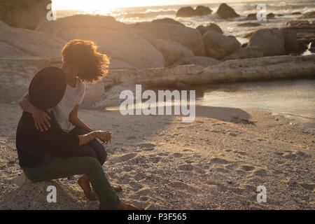 Couple looking at each other while sitting on beach Stock Photo