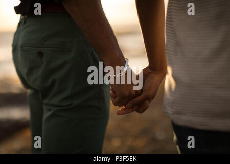 Couple holding hands in a beach during sunset Stock Photo