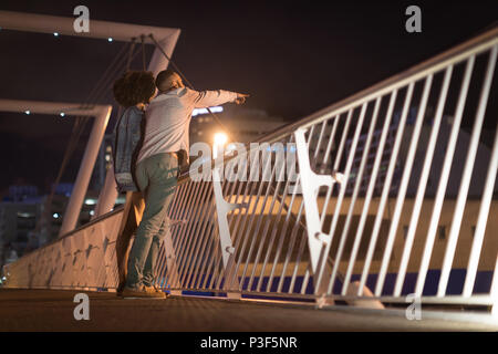 Couple pointing at distance while standing near railing Stock Photo