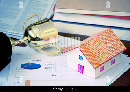 House model and trophy and income document reward on working table , finance concept. Stock Photo