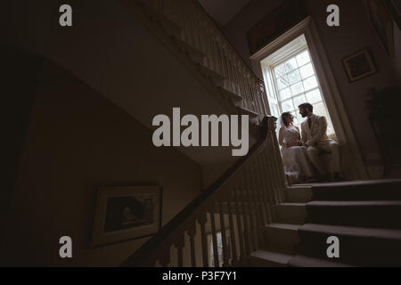 Bride and groom sitting on the window sill Stock Photo