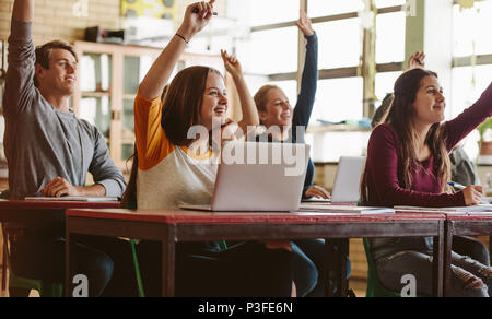 High school students rising hand up with smile in classroom to answer the question. Lecturer asking questions of students at classroom Stock Photo