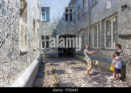 Family in Rosa's Passage, Łódź, Poland - a mosaic made up of small, irregular pieces of mirror on the facades of the houses Stock Photo