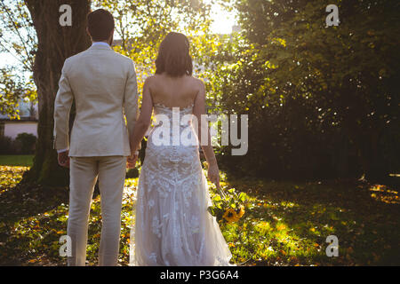 Bride and groom holding hands and standing in the garden Stock Photo