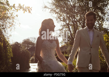 Bride and groom walking hand in hand in the garden Stock Photo