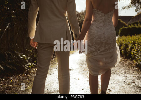 Bride and groom walking hand in hand in the garden Stock Photo