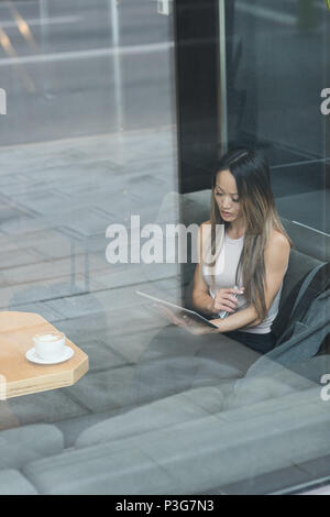 Asian businesswoman sitting alone using her tablet