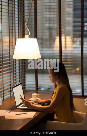 Businesswoman using her mobile phone while working on laptop Stock Photo