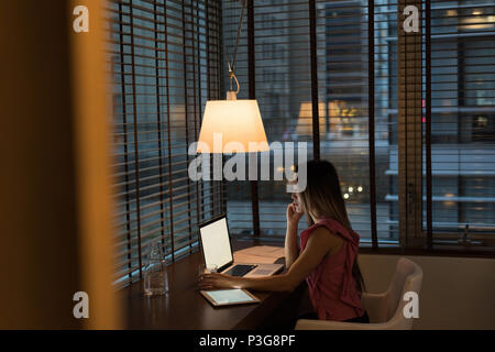 Businesswoman sitting on chair working on her laptop Stock Photo
