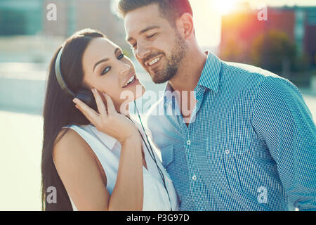 Young trendy caucasian couple in sunset woman with headphones Stock Photo