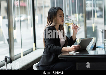 Businesswoman having champagne while working on tablet Stock Photo