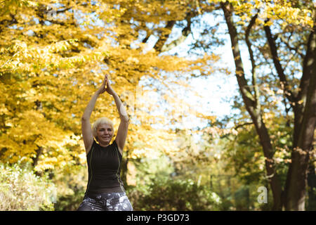 Senior woman practicing yoga in a park