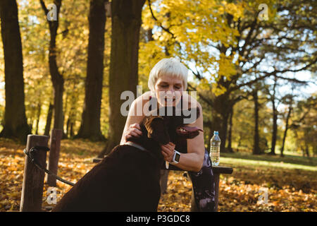 Senior woman in a park stoking her dog
