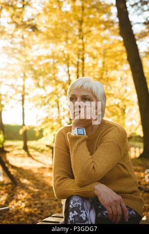 Thoughtful senior woman sitting in a park Stock Photo