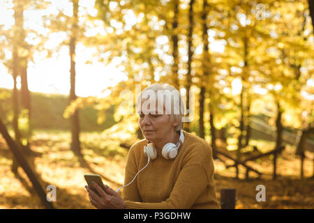 Senior woman using her mobile phone in the park Stock Photo