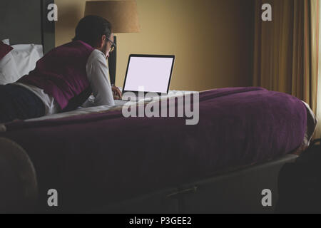 Businessman using laptop on bed Stock Photo