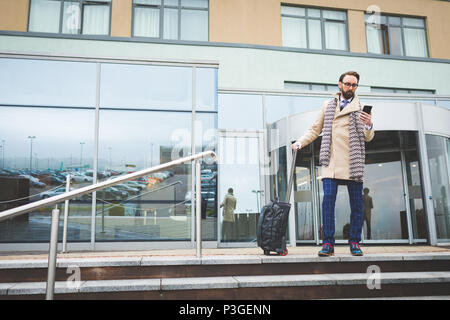 Businessman walking out of the hotel while using mobile phone Stock Photo